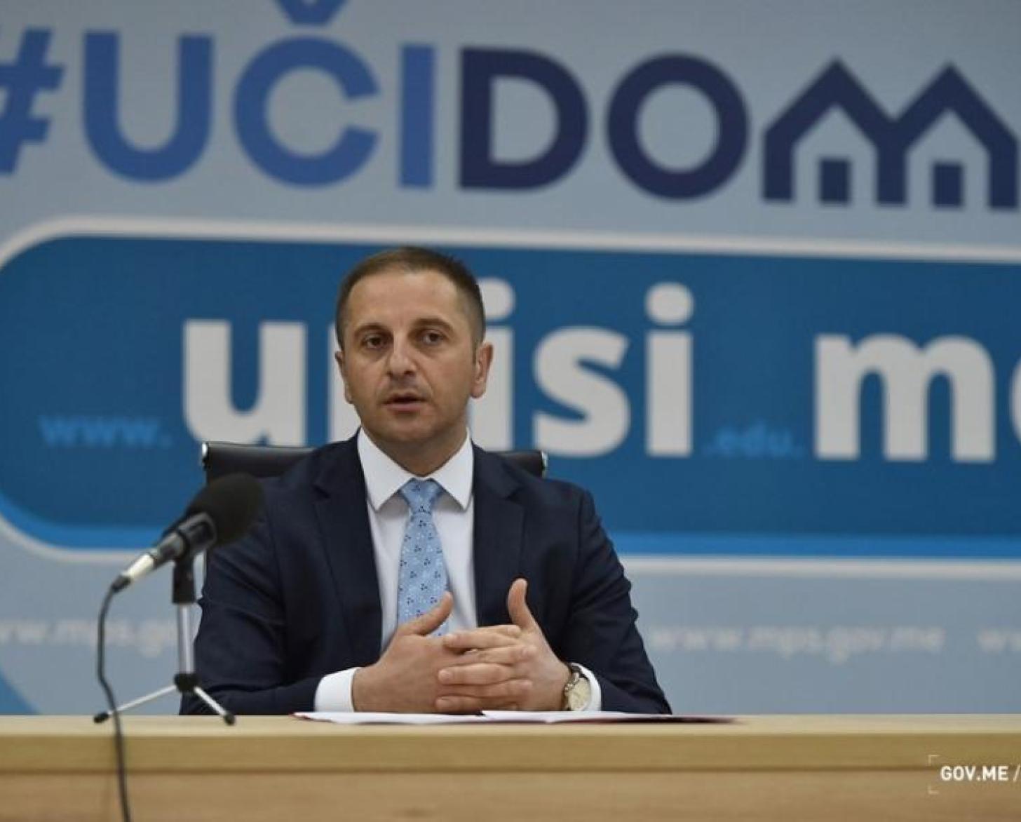 The photo shows the Minister of Education speaking to an audience during a panel discussion.