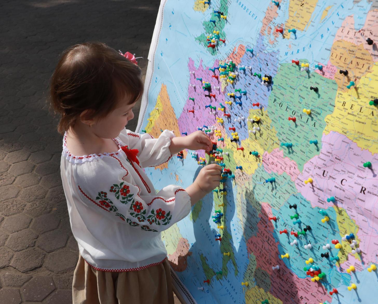 A little girl touches the thumbtacks placed on a map of the country.