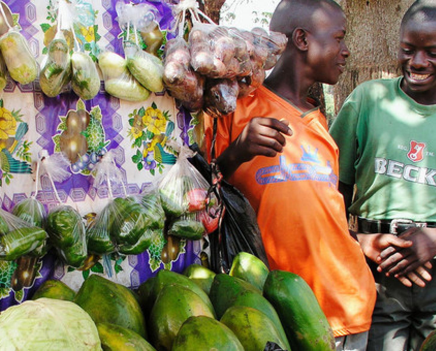 Dos vendedores del mercado charlan junto a un puesto de verduras en un mercado de Kampala, Uganda.