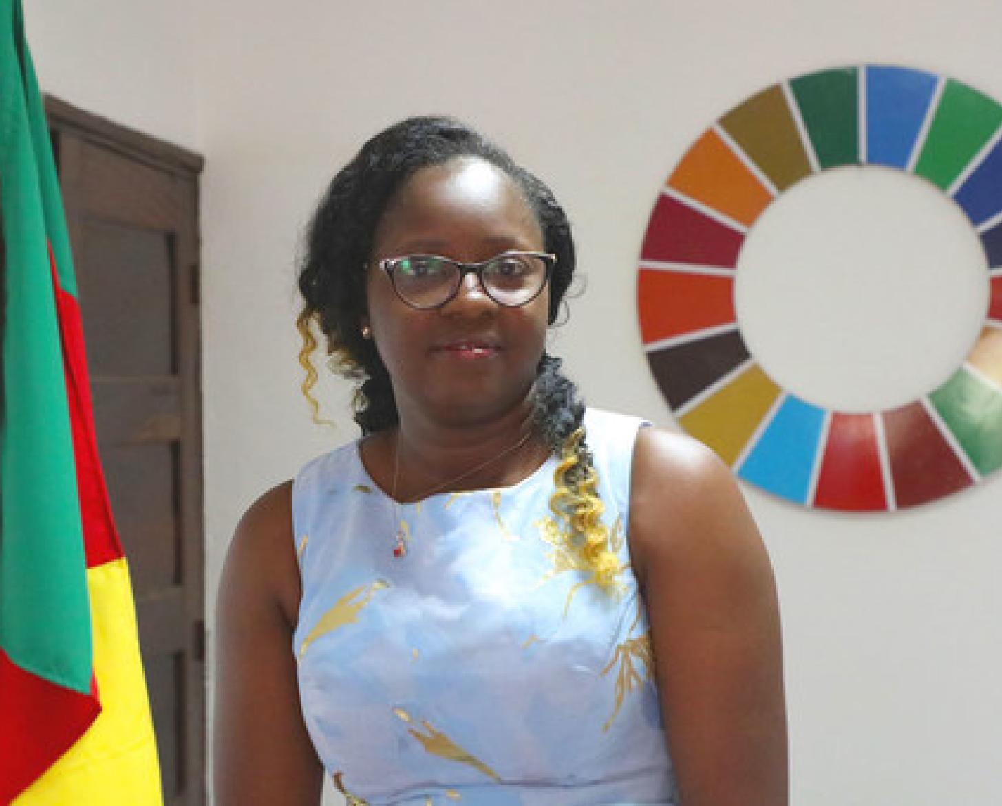 Photo showsCecile Mawe, founder and President of Jeunes en Action pour le Développement Durable (JADD), Cameroon., besides the Cameroon flag and the SDG wheel.