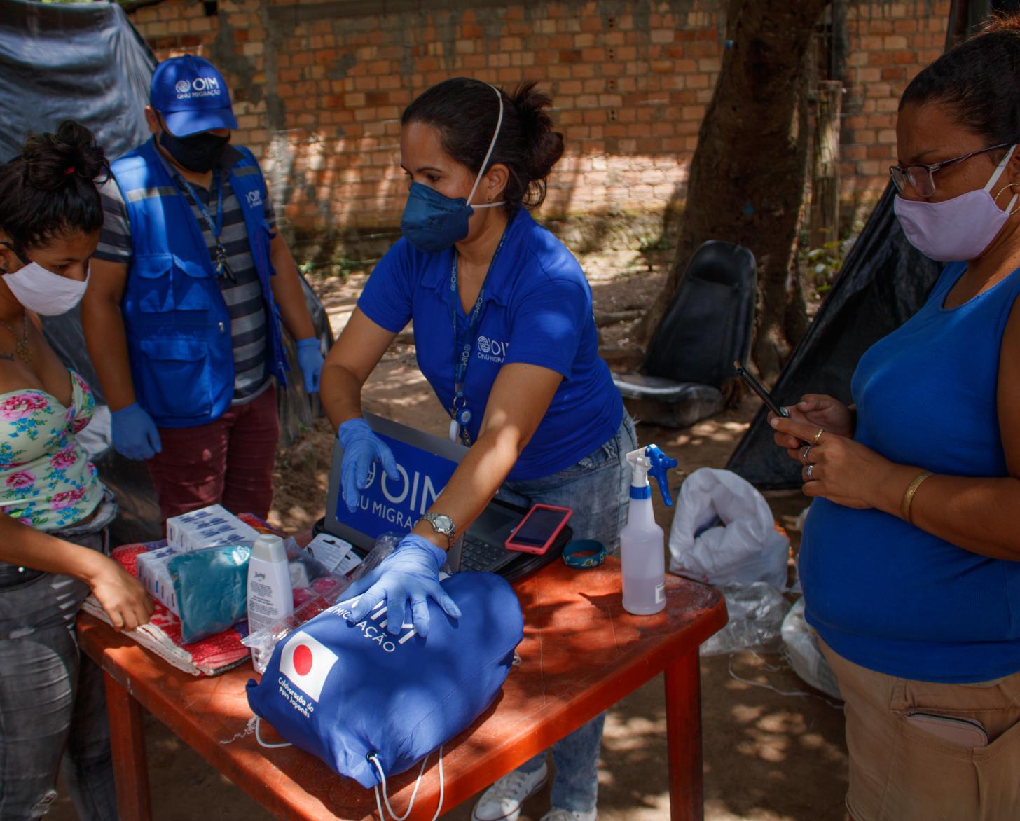 El personal de la OIM explica a los residentes qué contiene cada kit esencial donado.