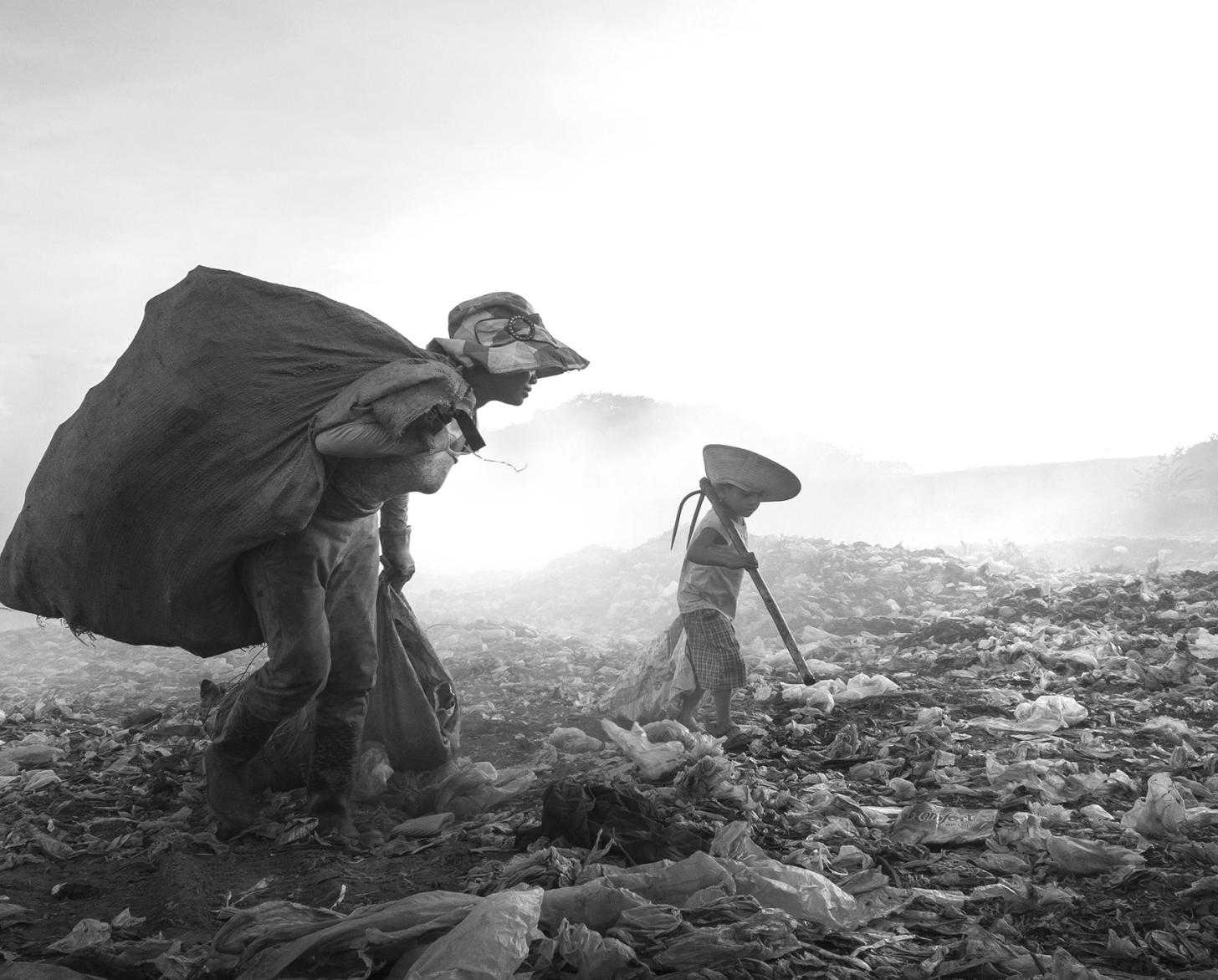 الأم والطفل يبحثان عن أشياء ثمينة - البلاستيك القابل لإعادة التدوير والأشياء الصغيرة التي يمكن إعادة بيعها.