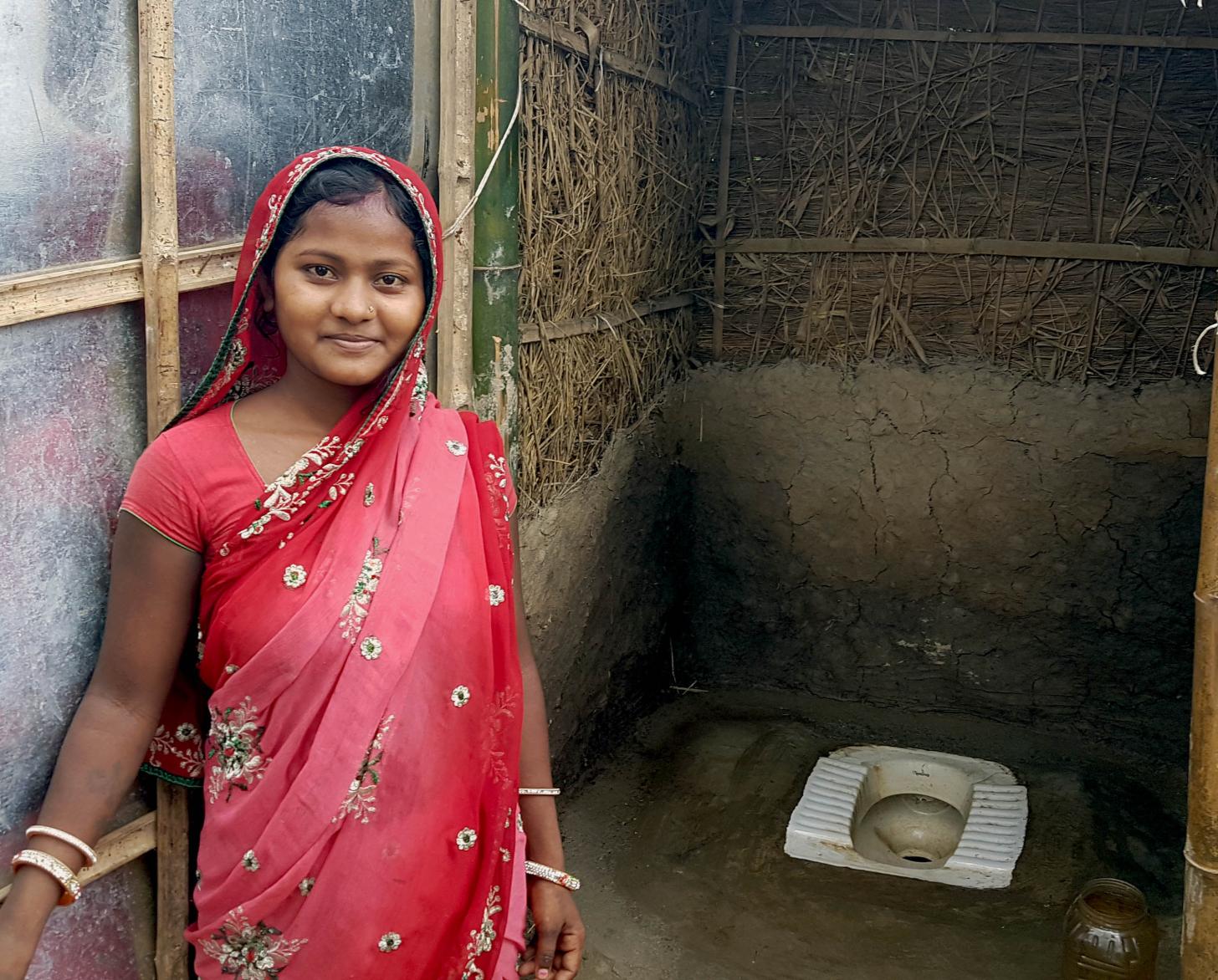 فتاة صغيرة تبتسم وهي تقف أمام المراحيض في بلباري.