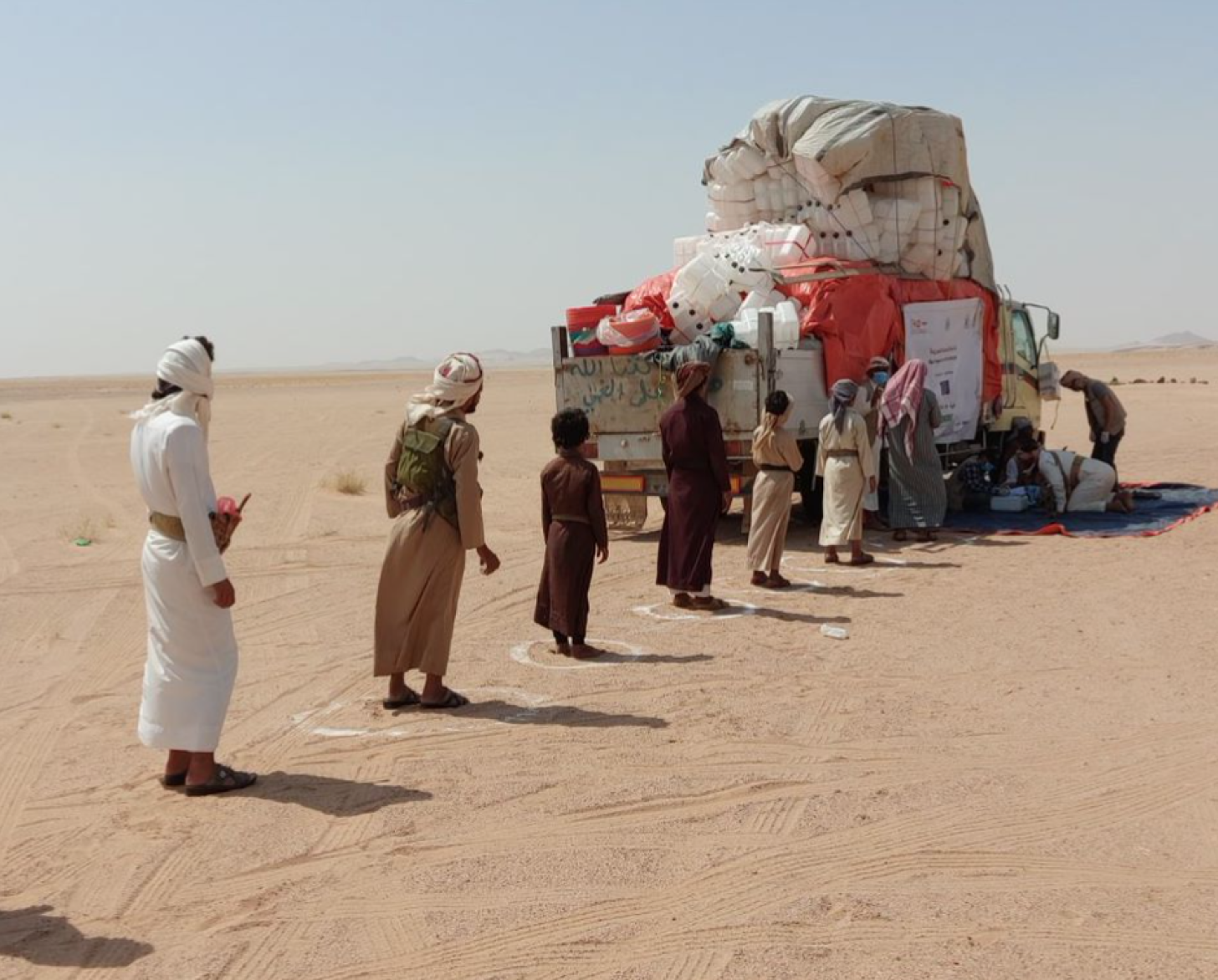 Los desplazados se colocan a dos metros de distancia mientras esperan en la línea de distribución de respuesta rápida en Al Jawf.