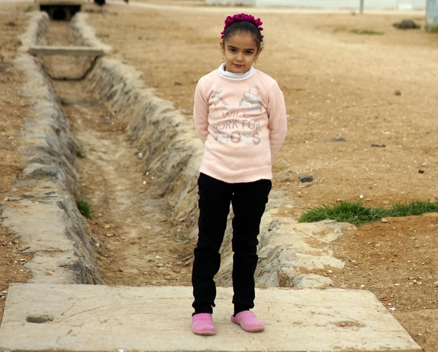 Laila, 10 stands outside across from her home. 
