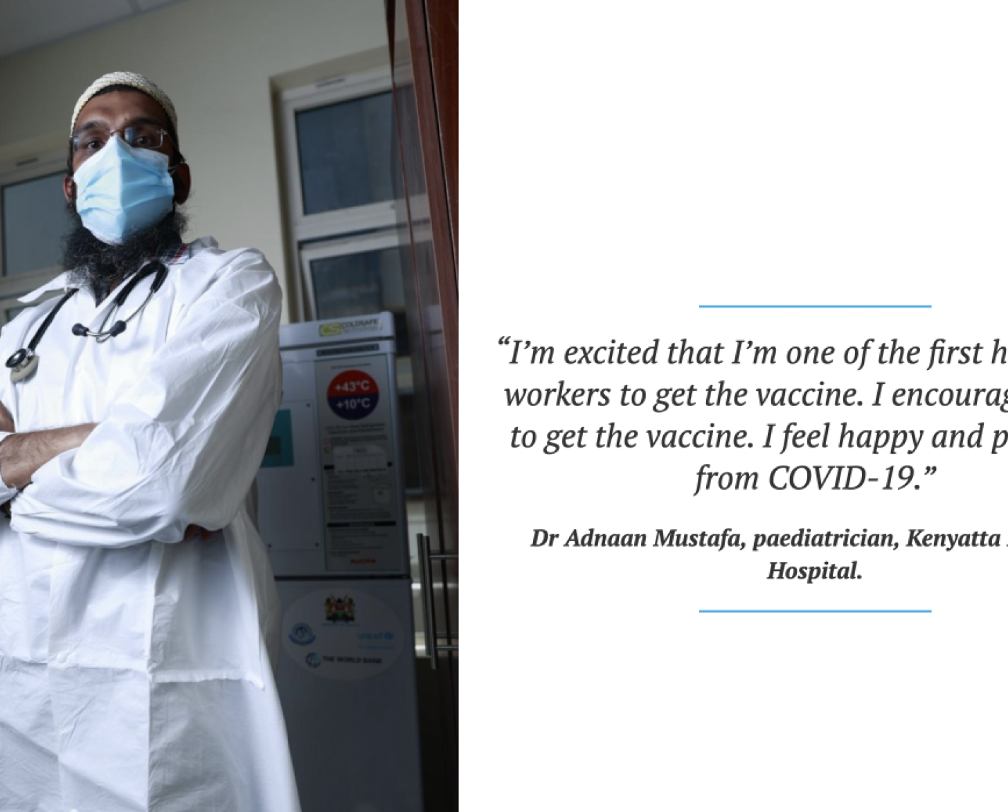A man in a white lab coat and blue surgical mask has his arms folded as he looks at the camera.
