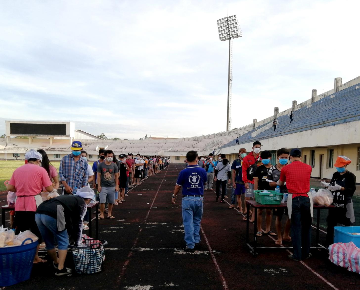 Many people line up in two lines to receive food and supplies. 