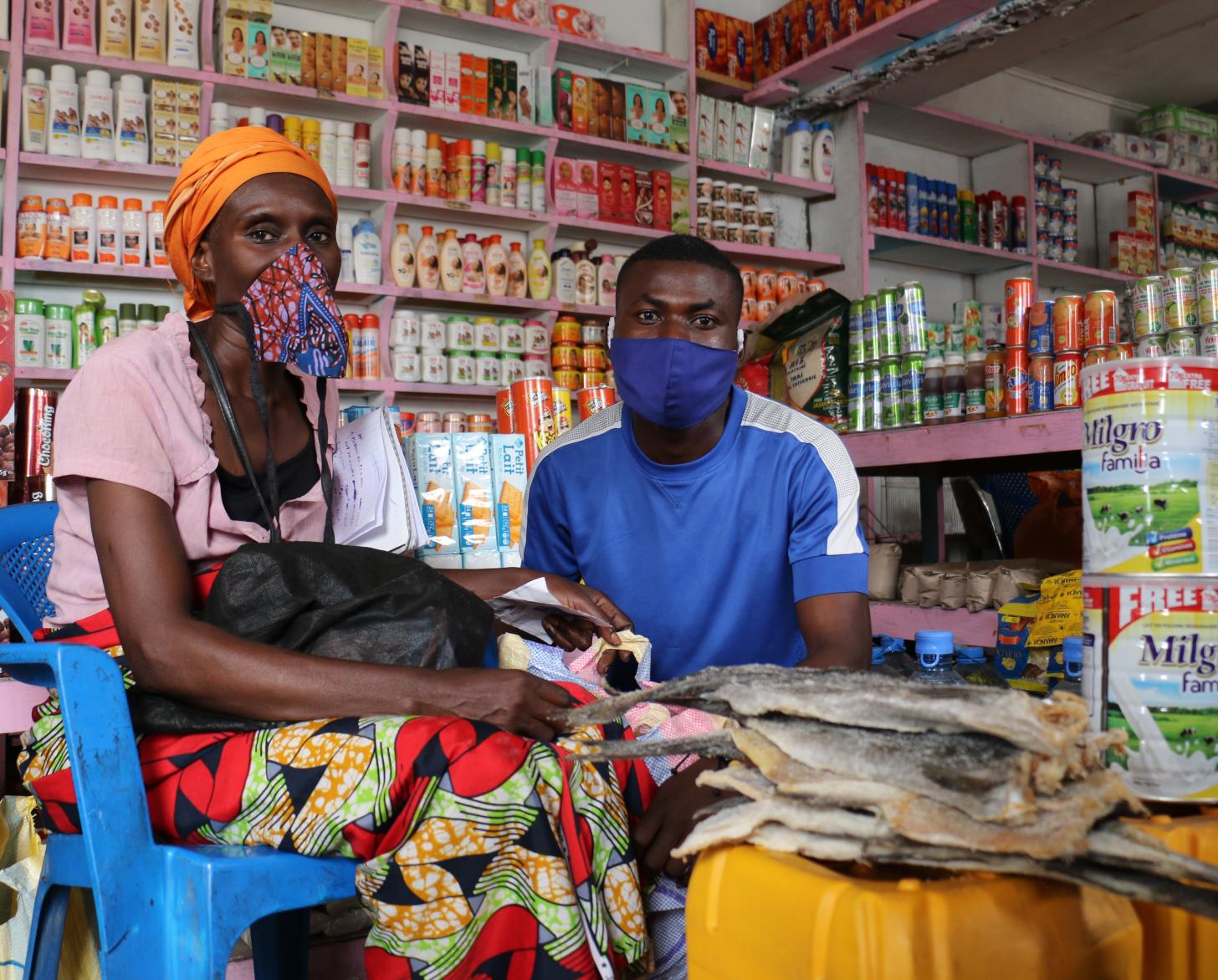 Una mujer y un hombre con mascarilla sentados en el mercado local.