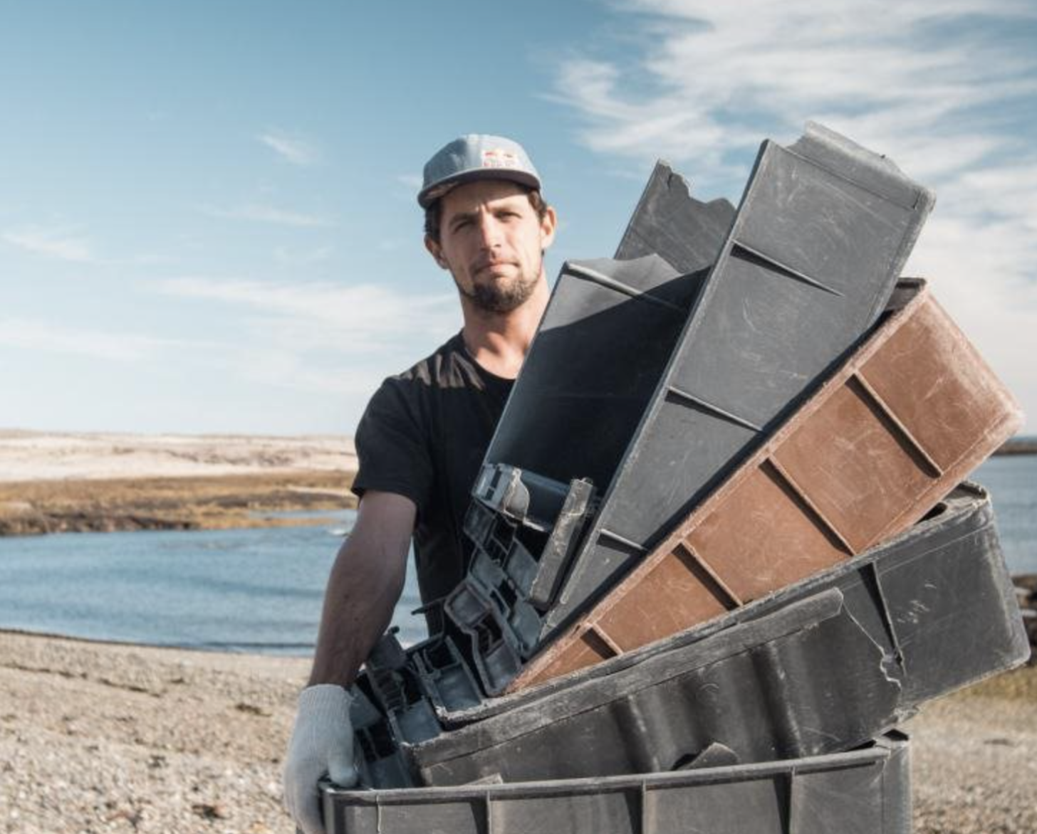 A man in a black shirt, white gloves and a hat holds plastic boxes.