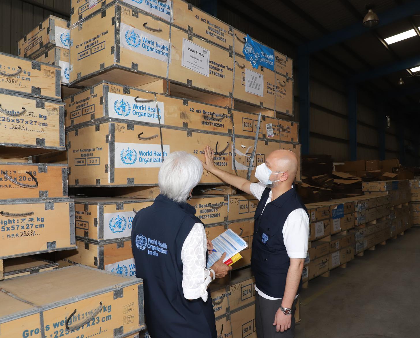 Two people examen a large shipment of medical supplies. 