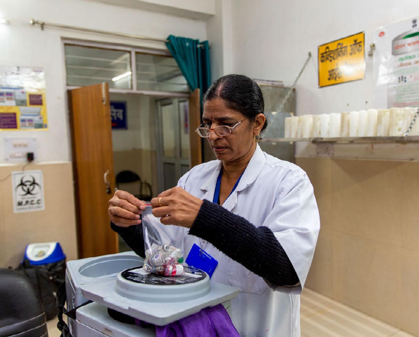 A medical professional collects vaccines and vials in a plastic bag. 