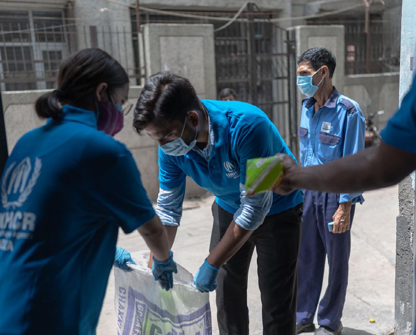 Two people work together to set up trash bags. 