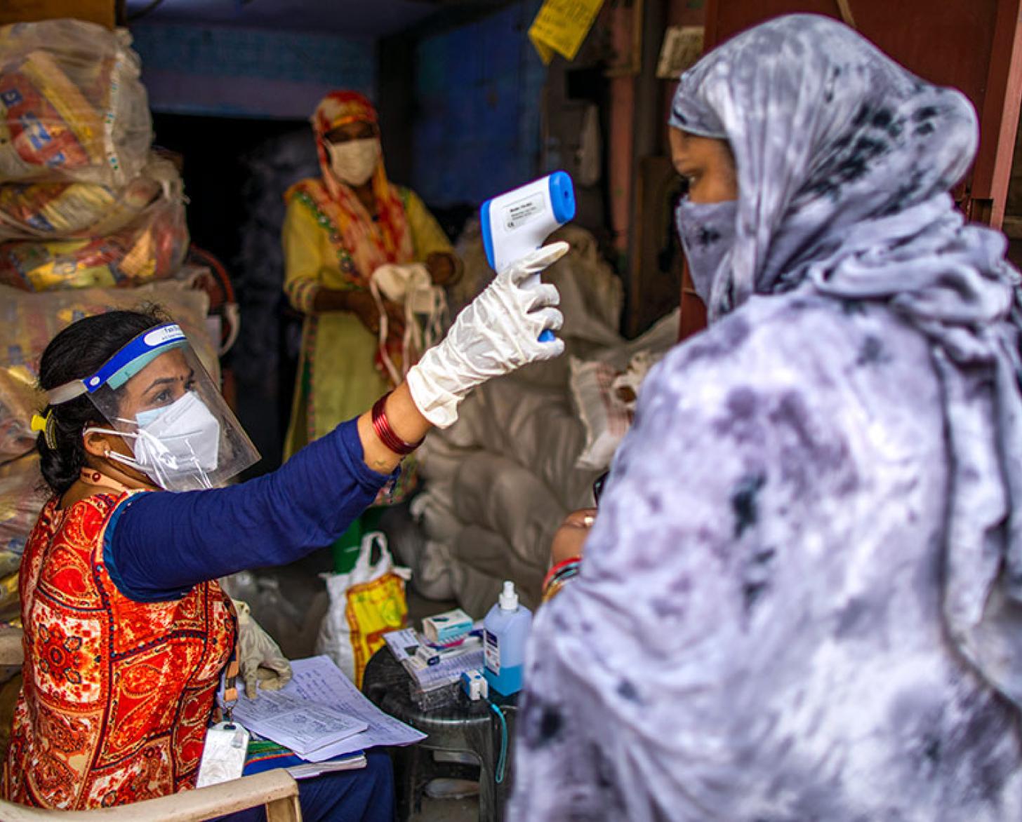 A health care professional takes a woman's temperature with a touch-less thermometer. 