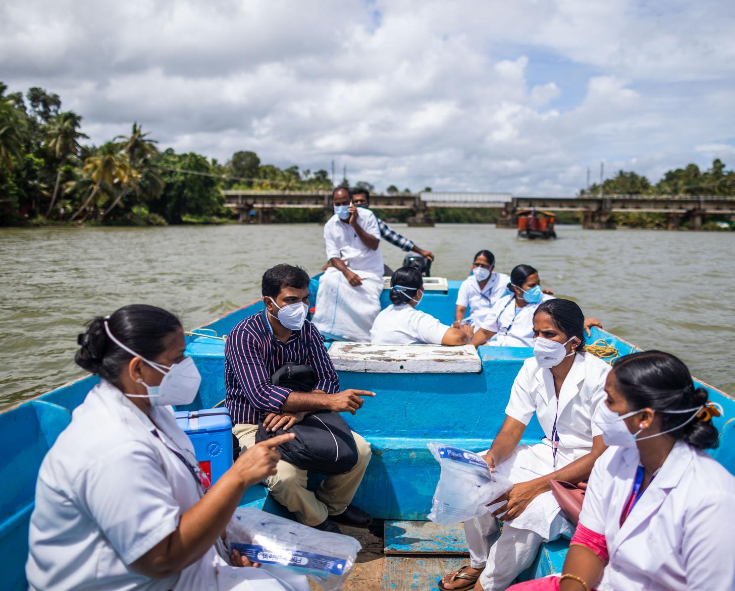 En Inde, des professionnels de santé portant chacun un masque de protection respiratoire voyagent en bateau à destination de l'île de Munroe, dans le sud du pays, pour y livrer des vaccins anti COVID-19.