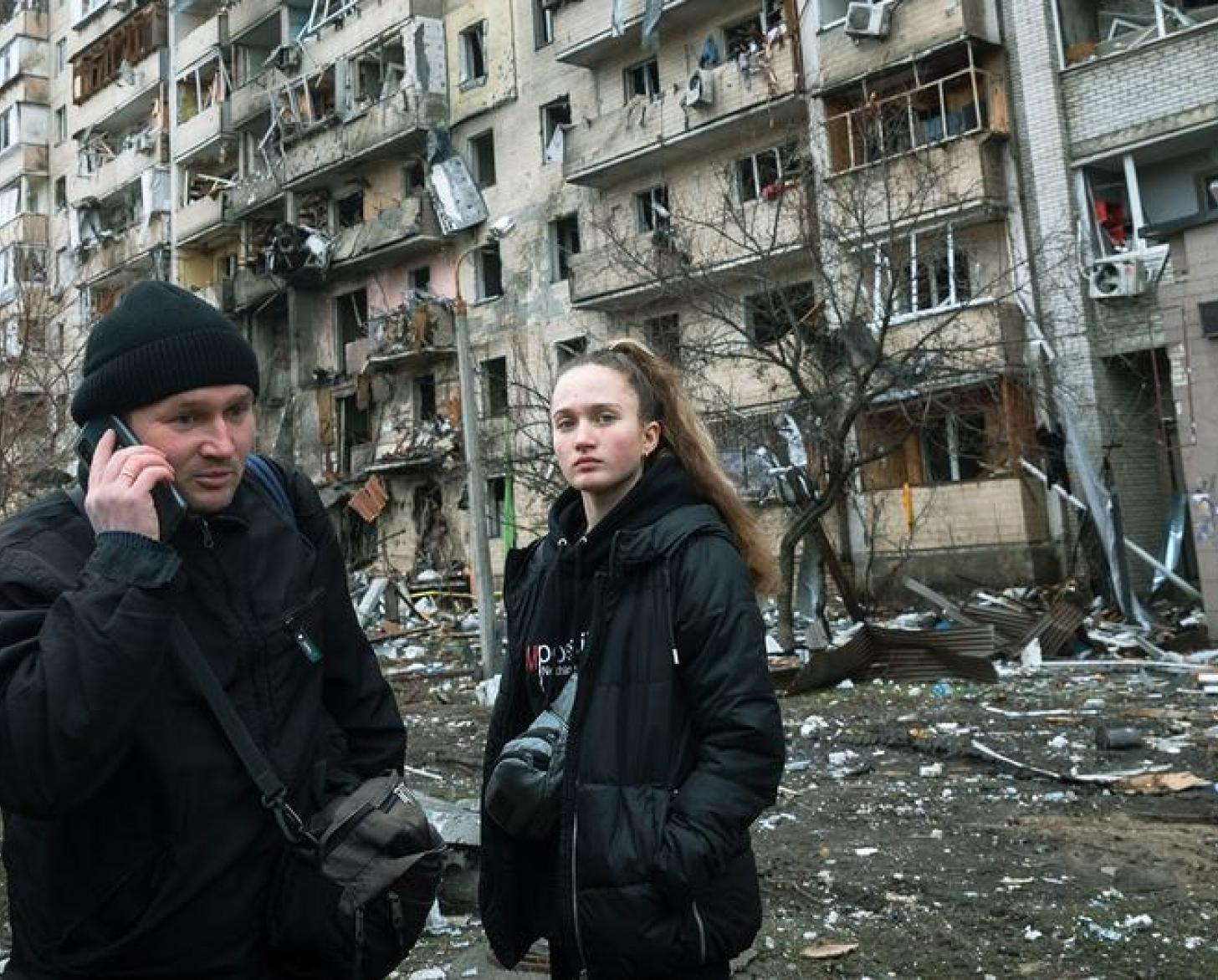 Le 25 février 2022 à Kiev, en Ukraine, un homme appelle de la famille, alors qu'il se trouve devant un immeuble endommagé par les opérations militaires.