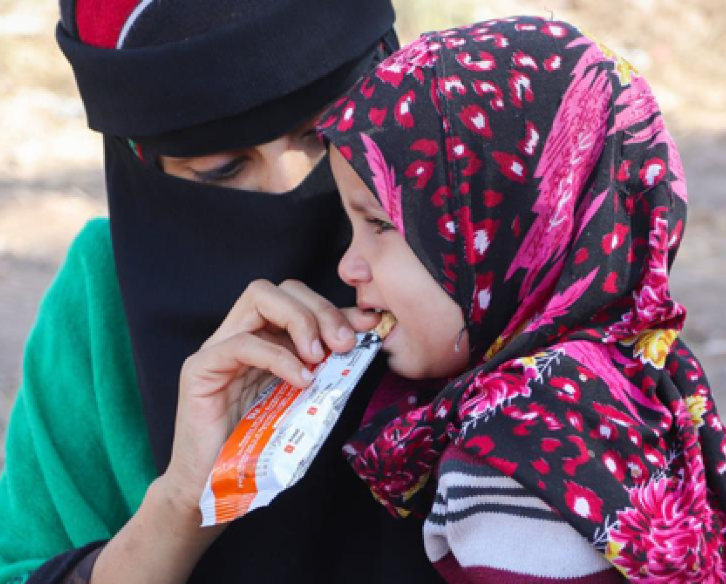 Una mujer da de comer a una niña un nutritivo refrigerio.