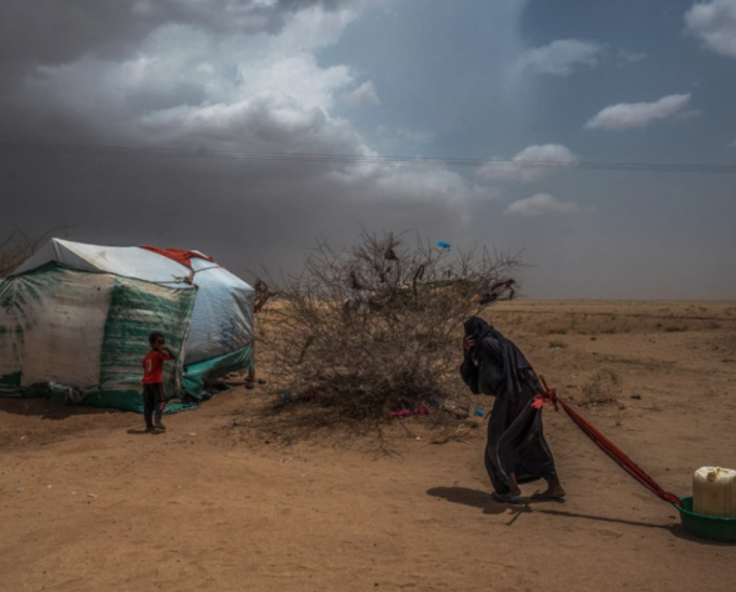 Una mujer arrastra agua hasta su tienda.