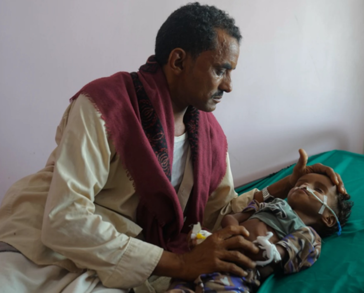 Un hombre mira a su sobrino bebé en una cama de hospital.