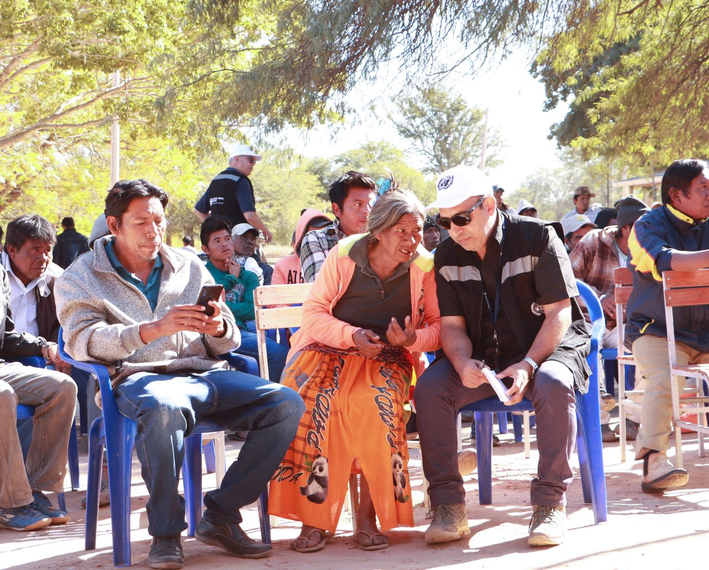 En un espacio exterior, con personas sentadas a manera de audiencia, una de las presentes, Catalina Martinez, de la comunidad nivacle en Paraguay, conversa con un colega de la OCHA.