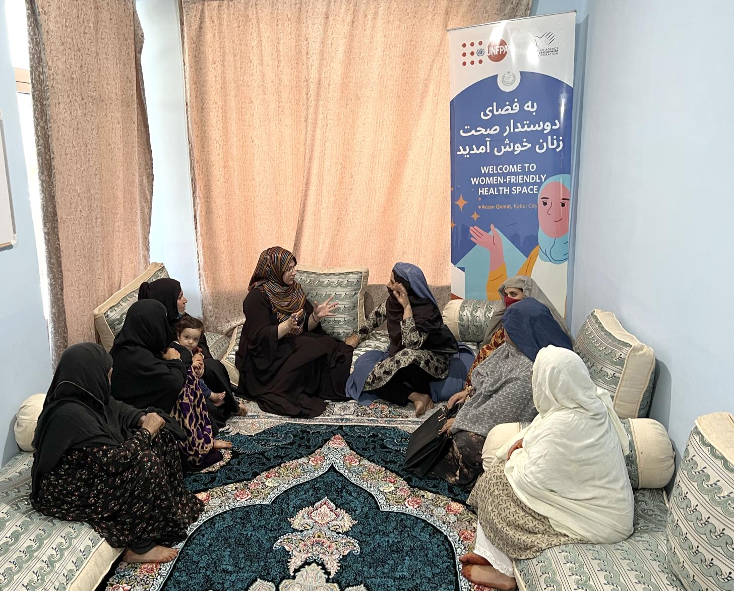 8 نساء محجبات يجلسن في نصف دائرة، تتحدث إحداهن بينما تستمع الأخريات.