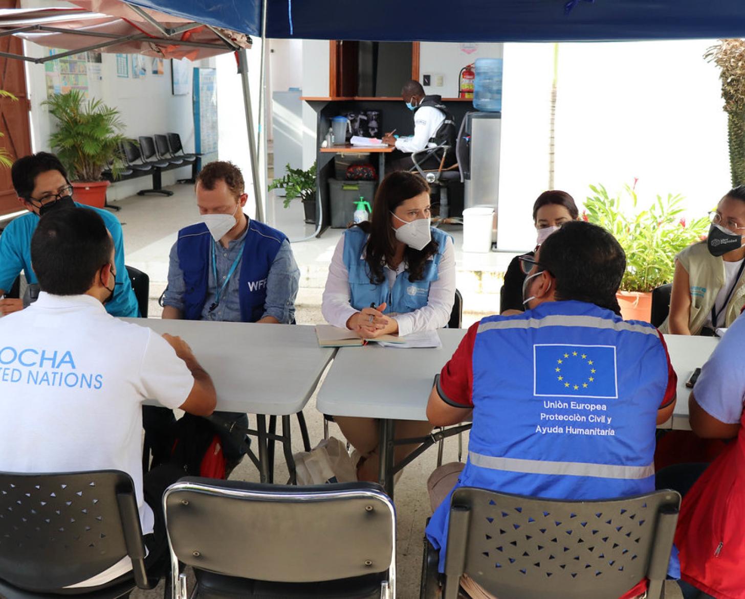 Plusieurs personnes sont assises autour d'une table rectangulaire : la Coordonnatrice résidente de l'ONU en Équateur, Lena Savelli, au centre, discute avec des collègues de différentes entités onusiennes et organisations travaillant sur le terrain. 