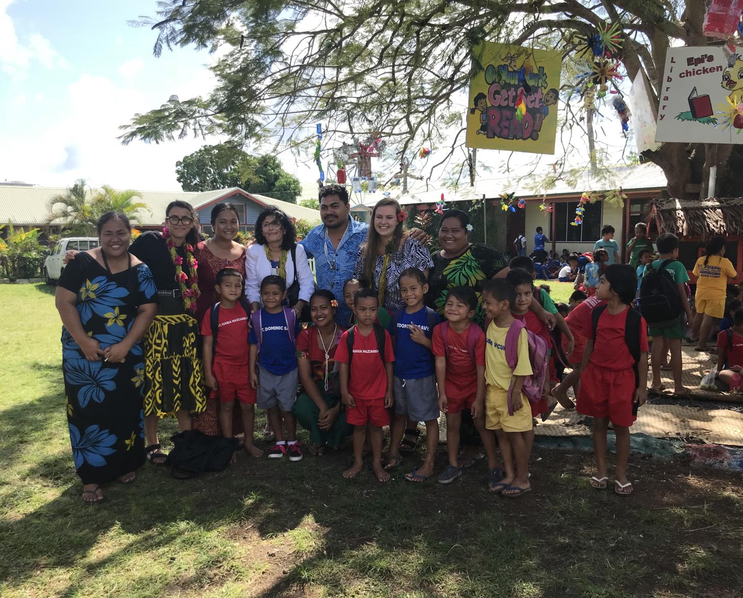 7 بالغين و 9 أطفال يقفون تحت شجرة في حدث تربوي.