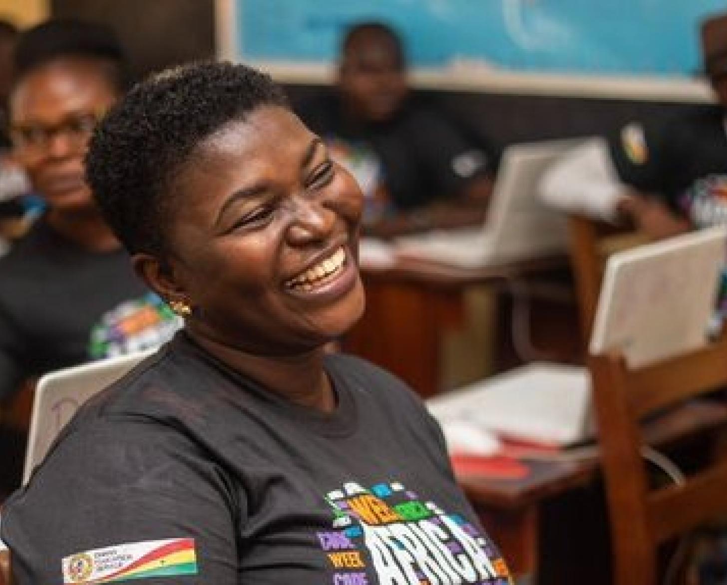 صورة لامرأة شابة بشعر قصير ترتدي قميصًا يحمل شعار Africa Code Week وهي تضحك.