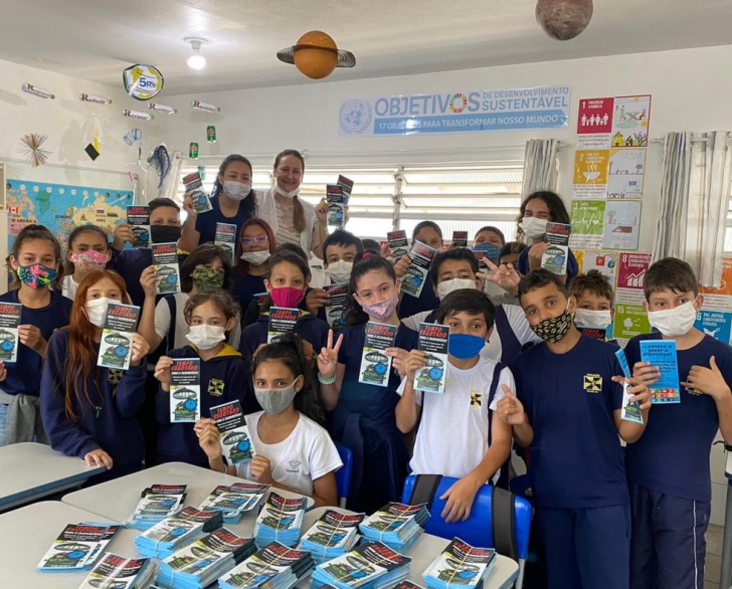 一张同学合影显示，小学生和他们的老师站在一起，戴着面罩，展示着他们的事业成果。