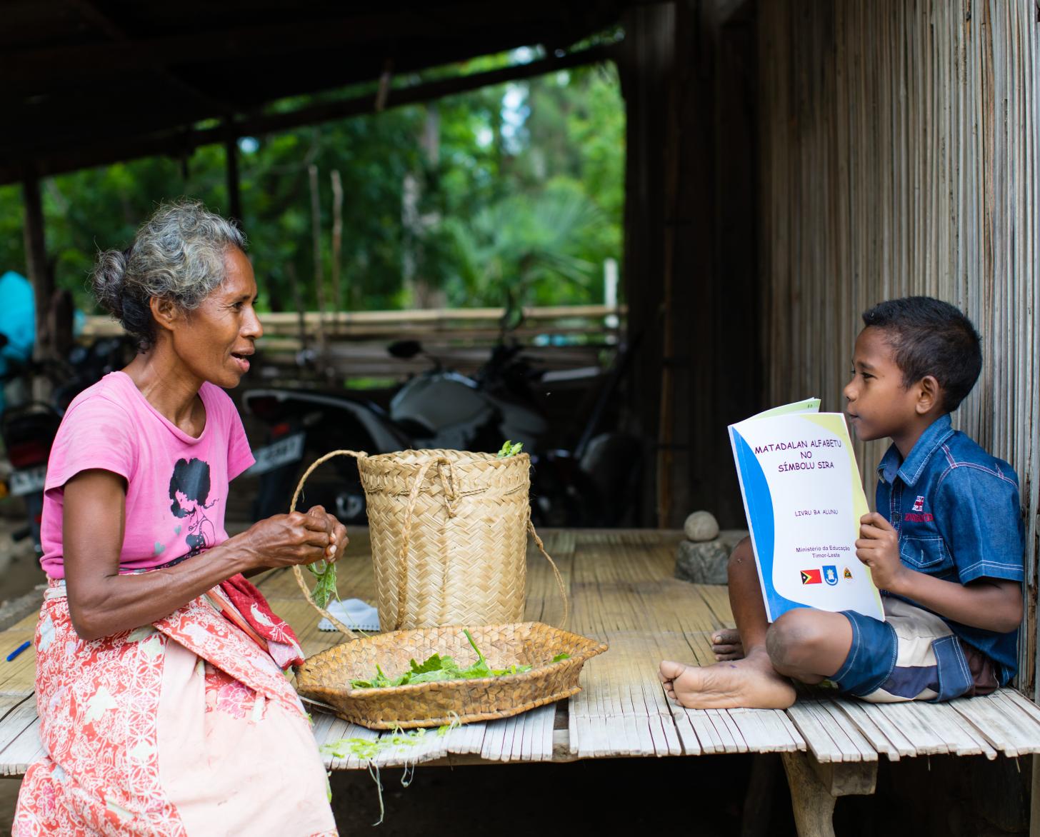 Una mujer y un niño se sientan juntos al lado de una cabaña.