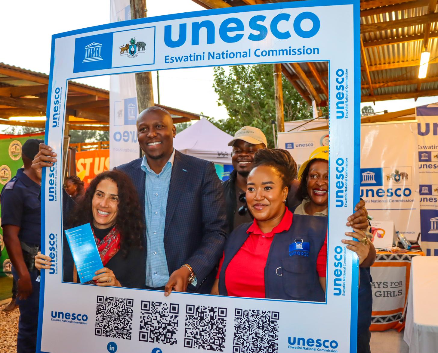 Three people are posing in front of a photo frame