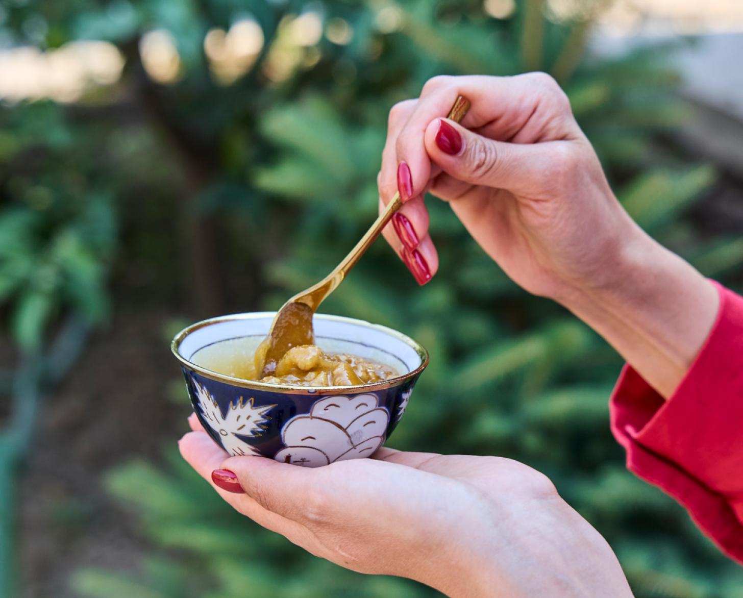 A woman stirs some fresh honey in a small bowl.