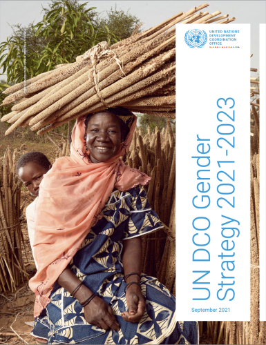 A woman is sitting in a filed and smiling at the camera. 