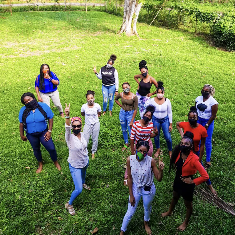 Varias chicas con máscaras faciales se paran en grupo mientras miran a la cámara.