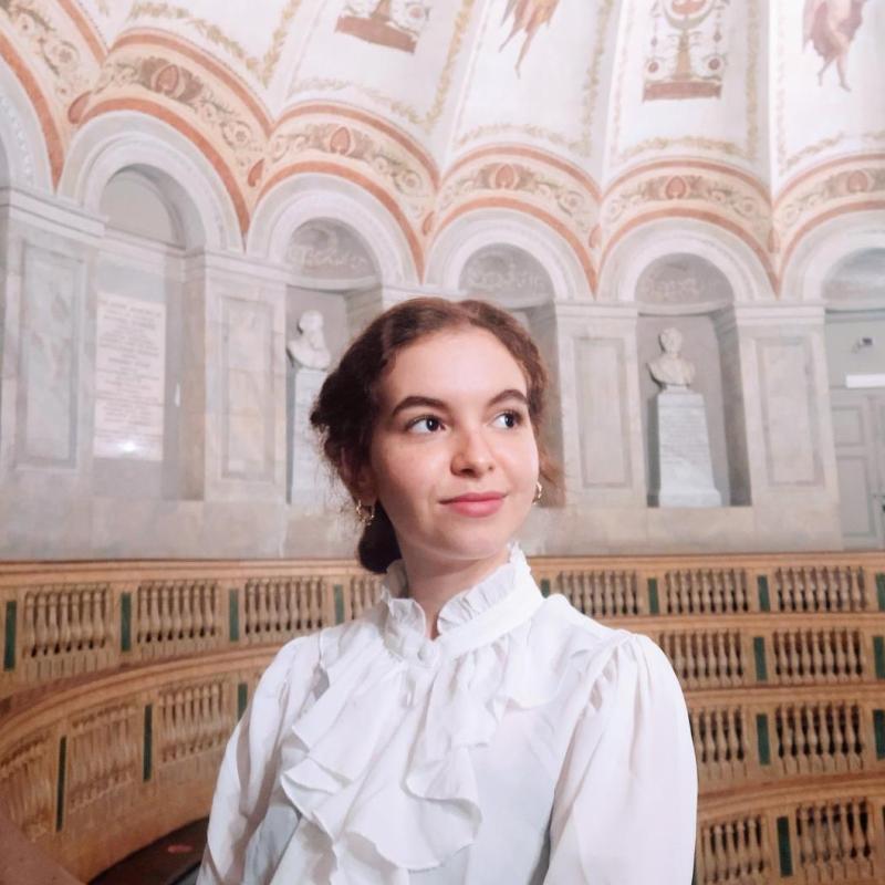 A woman in a white shirt looks off into the distance. 